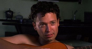 Movie still from “El Mariachi” (1992), directed by Robert Rodriguez – A person holding a guitar; Close Up shot, High angle