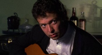 Movie still from “El Mariachi” (1992), directed by Robert Rodriguez – A man sitting in front of an acoustic guitar; Close Up shot, Low angle