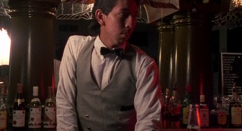 Movie still from “El Mariachi” (1992), directed by Robert Rodriguez – A man in a vest and bow tie standing at a bar; Medium shot, Low angle