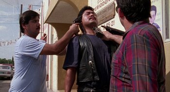 Movie still from “El Mariachi” (1992), directed by Robert Rodriguez – A man is being held up by two other men; Medium shot, Over the shoulder angle