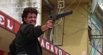 Movie still from “El Mariachi” (1992), directed by Robert Rodriguez – A man in a black jacket is holding a gun; Medium shot, Low angle