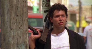 Movie still from “El Mariachi” (1992), directed by Robert Rodriguez – A man holding a gun while standing next to a pole; Medium shot, Low angle
