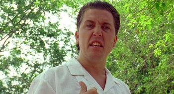 Movie still from “El Mariachi” (1992), directed by Robert Rodriguez – A person wearing a white shirt with trees in the background; Close Up shot, Low angle