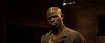 Movie still from “Elephant White” (2011), directed by Prachya Pinkaew – A man with a bald head is looking at the camera; Close Up shot, Low angle