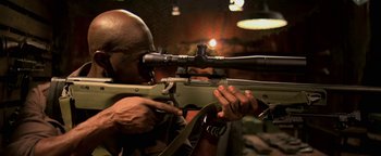 Movie still from “Elephant White” (2011), directed by Prachya Pinkaew – A man is holding a rifle and aiming it with a rifle scope; Close Up shot, High angle