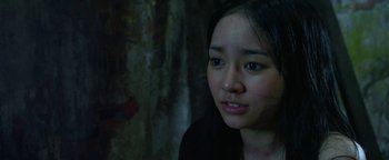 Movie still from “Elephant White” (2011), directed by Prachya Pinkaew – A young asian woman looking at the camera; Close Up shot, Low angle