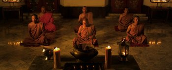 Movie still from “Elephant White” (2011), directed by Prachya Pinkaew – A group of monks sitting around a bowl of food; Wide shot, High angle