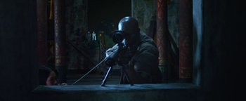 Movie still from “Elephant White” (2011), directed by Prachya Pinkaew – A man with a rifle aiming at something in the dark; Medium shot, High angle