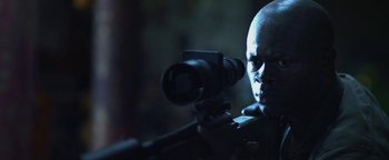 Movie still from “Elephant White” (2011), directed by Prachya Pinkaew – A bald man with a gun and a camera in his hand; Close Up shot, Low angle