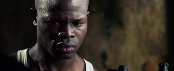 Movie still from “Elephant White” (2011), directed by Prachya Pinkaew – A man's face in a dark room; Close Up shot, Low angle