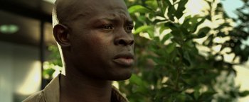 Movie still from “Elephant White” (2011), directed by Prachya Pinkaew – A person's face in front of a tree; Close Up shot, Low angle