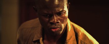 Movie still from “Elephant White” (2011), directed by Prachya Pinkaew – A man's face in a brown shirt; Close Up shot, Low angle