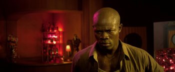 Movie still from “Elephant White” (2011), directed by Prachya Pinkaew – A man with a bald head is standing in front of a red light; Close Up shot, Low angle