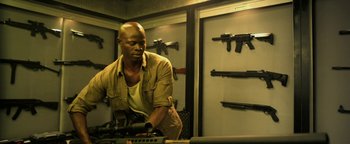 Movie still from “Elephant White” (2011), directed by Prachya Pinkaew – A man in a room holding a gun and looking down; Medium shot, Low angle