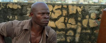 Movie still from “Elephant White” (2011), directed by Prachya Pinkaew – A black man with a bald head is looking into the distance; Close Up shot, High angle