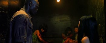 Movie still from “Elephant White” (2011), directed by Prachya Pinkaew – A group of people sitting in a dark room; Medium shot, High angle