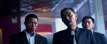 Movie still from “Elephant White” (2011), directed by Prachya Pinkaew – Two men in suits and ties standing next to each other; Close Up shot, Low angle