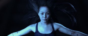 Movie still from “Elephant White” (2011), directed by Prachya Pinkaew – A young woman with long black hair in the dark; Close Up shot, Low angle