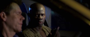 Movie still from “Elephant White” (2011), directed by Prachya Pinkaew – A man with a bald head is holding a cell phone; Close Up shot, Over the shoulder angle