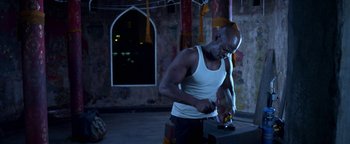 Movie still from “Elephant White” (2011), directed by Prachya Pinkaew – A man in a white tank top is holding a knife; Medium shot, Low angle