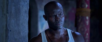 Movie still from “Elephant White” (2011), directed by Prachya Pinkaew – A man in a white tank top is looking at the camera; Close Up shot, Low angle