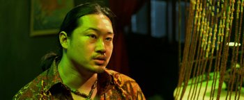 Movie still from “Elephant White” (2011), directed by Prachya Pinkaew – A man with a beard is looking at the camera; Close Up shot, Low angle