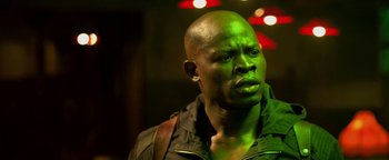 Movie still from “Elephant White” (2011), directed by Prachya Pinkaew – A man in a green jacket looking to his left; Close Up shot, Low angle