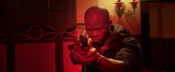 Movie still from “Elephant White” (2011), directed by Prachya Pinkaew – A man holding a gun in a room with red lighting; Close Up shot, Low angle