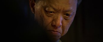 Movie still from “Elephant White” (2011), directed by Prachya Pinkaew – An older man looking down at his face; Extreme Close Up shot, Low angle