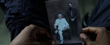 Movie still from “Elephant White” (2011), directed by Prachya Pinkaew – A person holding a picture of a man in a chair; Extreme Close Up shot, High angle