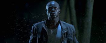 Movie still from “Elephant White” (2011), directed by Prachya Pinkaew – A man with a black shirt is standing in the dark; Close Up shot, Low angle