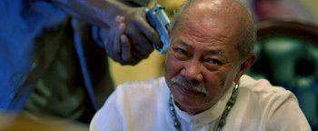 Movie still from “Elephant White” (2011), directed by Prachya Pinkaew – An older man getting his hair cut by a barber; Close Up shot, Over the shoulder angle
