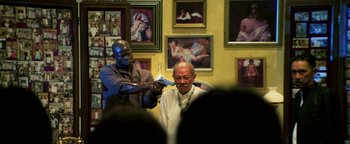 Movie still from “Elephant White” (2011), directed by Prachya Pinkaew – A man getting his hair cut by a bald man; Medium shot, Over the shoulder angle