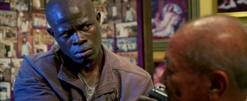 Movie still from “Elephant White” (2011), directed by Prachya Pinkaew – A person wearing a brown jacket; Close Up shot, Over the shoulder angle