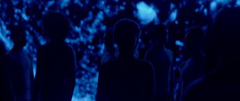 Movie still from “Ema” (2019), directed by Pablo Larraín – A group of people standing in a dark room; Medium shot, High angle