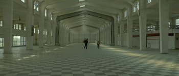 Movie still from “Ema” (2019), directed by Pablo Larraín – Two people are walking in an empty building; Extreme Wide shot, High angle