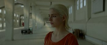 Movie still from “Ema” (2019), directed by Pablo Larraín – A woman with blonde hair is standing in a hallway; Close Up shot, Low angle