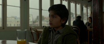 Movie still from “Ema” (2019), directed by Pablo Larraín – A young boy sitting at a table in front of a window; Close Up shot, Low angle