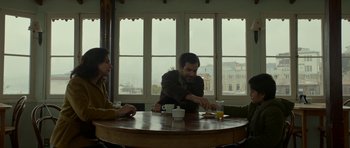 Movie still from “Ema” (2019), directed by Pablo Larraín – Two people sitting at a table with a cup of coffee; Medium shot, Over the shoulder angle
