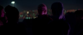 Movie still from “Ema” (2019), directed by Pablo Larraín – Two people standing in front of a city skyline at night; Medium shot, Over the shoulder angle