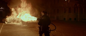 Movie still from “Ema” (2019), directed by Pablo Larraín – A man in a gas mask is holding a fire hose; Wide shot, Low angle