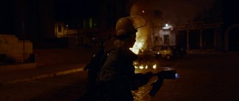 Movie still from “Ema” (2019), directed by Pablo Larraín – A person riding a motorcycle in front of a burning building; Medium shot, High angle