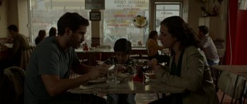 Movie still from “Ema” (2019), directed by Pablo Larraín – A man and a woman sitting at a table with a child; Medium shot, High angle