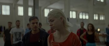 Movie still from “Ema” (2019), directed by Pablo Larraín – A woman with blonde hair is standing in front of a man; Close Up shot, Over the shoulder angle