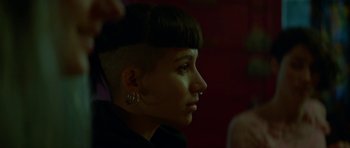 Movie still from “Ema” (2019), directed by Pablo Larraín – A woman with a shaved head looks to the side; Close Up shot, Over the shoulder angle