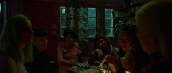 Movie still from “Ema” (2019), directed by Pablo Larraín – A group of people sitting at a table with food; Medium shot, High angle