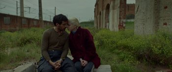 Movie still from “Ema” (2019), directed by Pablo Larraín – A man and a woman sitting next to each other on a bench; Medium shot, Low angle