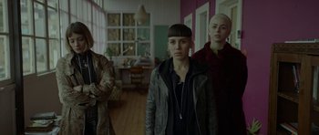 Movie still from “Ema” (2019), directed by Pablo Larraín – A group of people standing next to each other in a room; Medium shot, Low angle