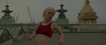 Movie still from “Ema” (2019), directed by Pablo Larraín – A woman in a red top is running; Medium shot, Low angle