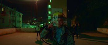 Movie still from “Ema” (2019), directed by Pablo Larraín – A person wearing a helmet and holding a hose; Medium shot, Over the shoulder angle